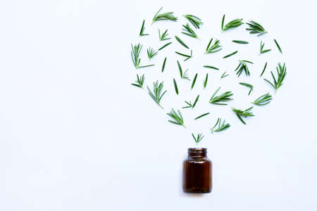 Medical bottle glass with fresh rosemary leaves isolated on white background. Heart shape