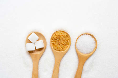 Wooden spoon with sugar on white granulated background. Top viewの写真素材