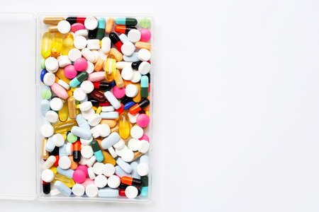 Colorful tablets with capsules and pills in plastic box on white background.の写真素材