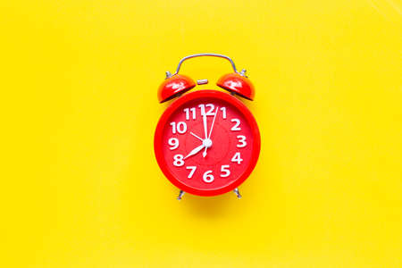 Red alarm clock ring on yellow background. Top view
