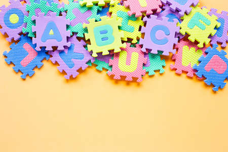 Alphabet puzzle on yellow background. Top viewの写真素材