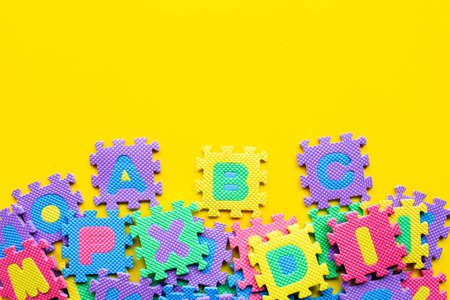 Alphabet puzzle on yellow background. Top viewの写真素材