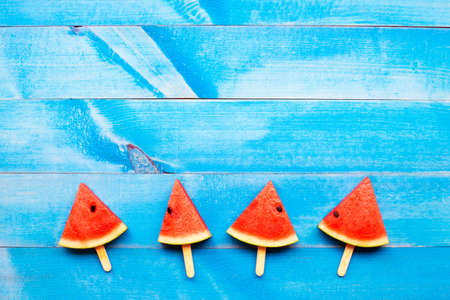 Watermelon slice on sticks on blue wooden background. Top view