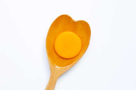 Egg yolk on wooden spoon on white background.