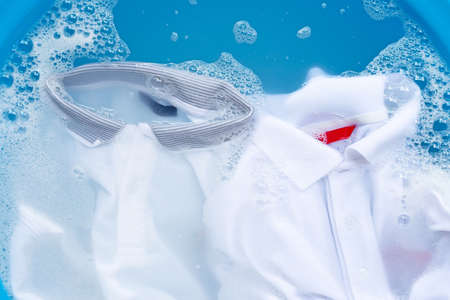 White polo shirts soak in powder detergent water dissolution, washing  cloth. Laundry concept