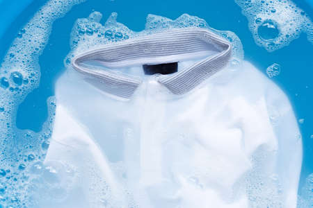 White polo shirt soak in powder detergent water dissolution, washing  cloth. Laundry concept