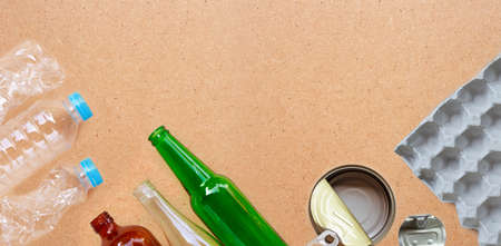 Recyclable garbage, plastic bottle, glass bottle, can and egg paper tray on brown plywood background. Copy spaceの写真素材
