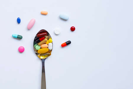Colorful tablets with capsules and pills on white background. Copy space
