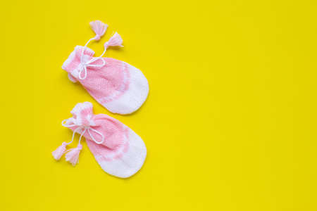 Baby gloves on yellow background. Top view