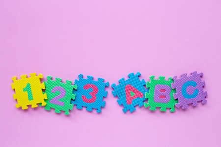 Alphabet puzzle with number puzzle on pink background. Top viewの写真素材