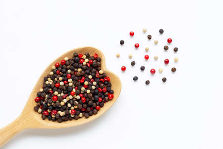 Black, red and white peppercorns with wooden spoon on white background.