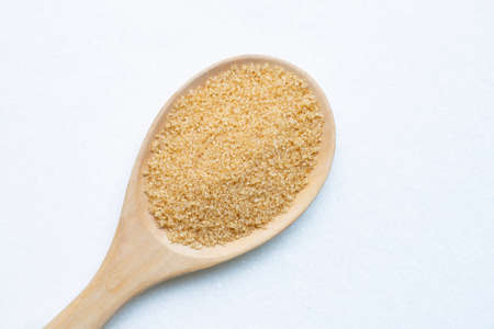 Wooden spoon with brown sugar on white granulated sugar. Top view