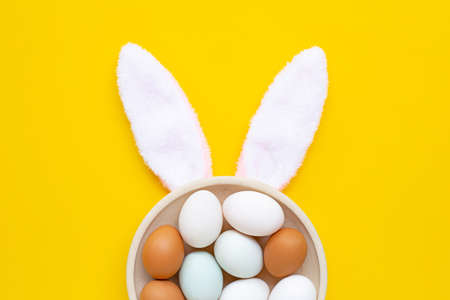 Top view of cute bunny ears with eggs on yellow background. Easter conceptの写真素材