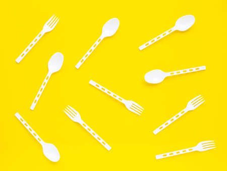 Plastic spoon and fork on yellow background. Top viewの写真素材