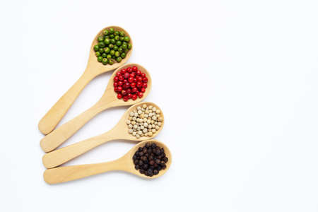 Green, red white and black peppercorns with wooden spoon on white background.の写真素材