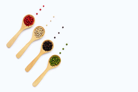 Green, red white and black peppercorns with wooden spoon on white background.の写真素材