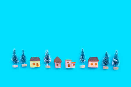 Merry Christmas and Happy Holidays, Miniature house with fir trees on blue background. Copy space の写真素材