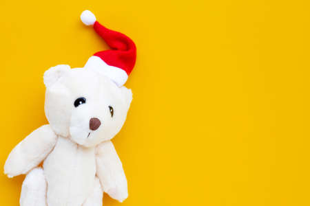 Toy bear wearing a santa hat on yellow background. Christmas holidays conceptの写真素材