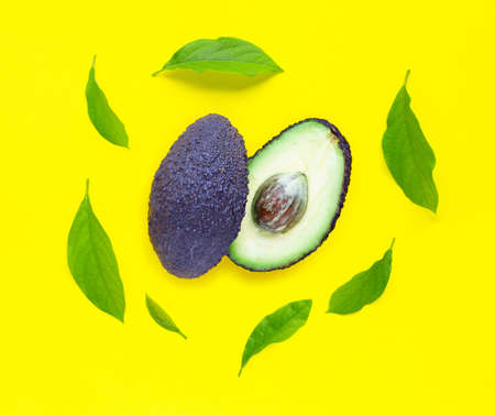 Avocado  with leaves on yellow background. Top view
