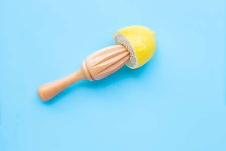 Fresh lemon with wooden juicer on blue background. Copy spaceの写真素材