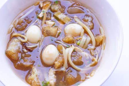 Braised fish maw in red gravy in bowl on white background.