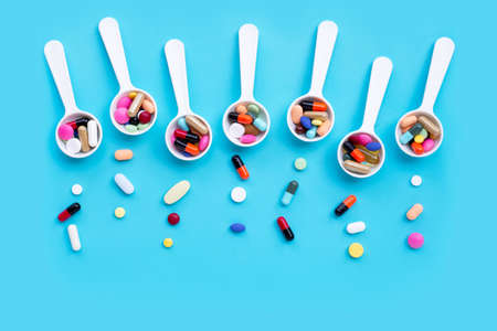 Colorful medicine pills, tablets and capsules on blue background. Copy spaceの写真素材
