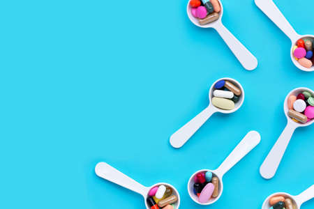 Colorful medicine pills, tablets and capsules on blue background. Copy space