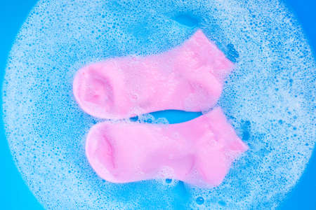 Pink  socks soaking in powder detergent water dissolution. Laundry concept. Top viewの写真素材