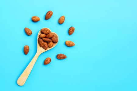 Almonds with wooden spoon on blue background. Copy spaceの写真素材