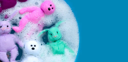 Soaking rabbit dolls with bear toys in laundry detergent water dissolution before washing. Laundry concept, Top view with blue background.の写真素材