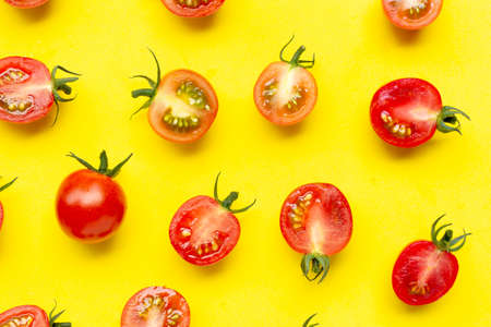Fresh tomatoes, whole and half cut isolated on yellow background. Top viewの写真素材