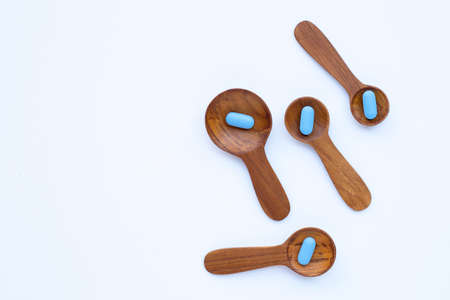 Medical blue pills with he wooden spoon on white background. Copy spaceの写真素材