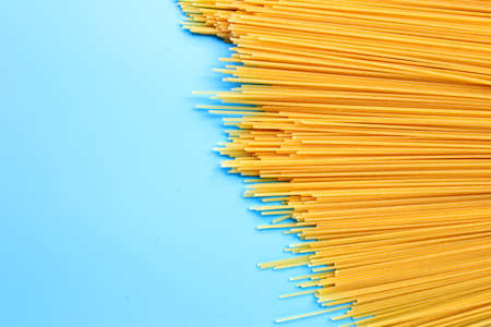 Yellow long spaghetti on blue background. Copy spaceの写真素材