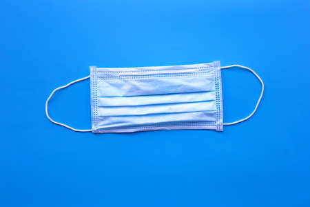 Surgical mask on blue background. Top view