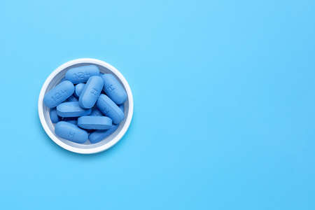 PrEP ( Pre-Exposure Prophylaxis) used to prevent HIV, on plastic pill bottle cap. Blue background,...