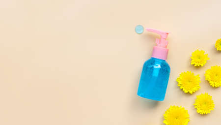 Alcohol hand sanitizer gel in pump bottle with yellow flower on cream color background. Copy spaceの写真素材
