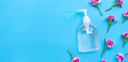 Alcohol hand sanitizer gel in pump bottle with carnation flower on blue background. Copy spaceの写真素材