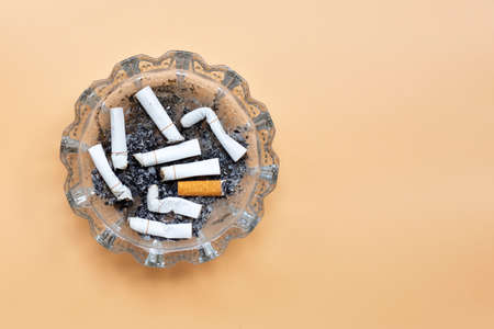 Smoked cigarettes on cream color background. Copy spaceの写真素材