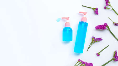 Alcohol hand sanitizer gel in pump bottles on yellow background with static flower, copy space. Hand...