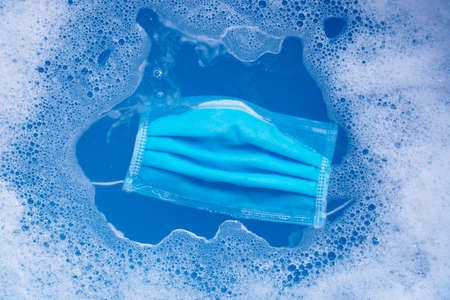 Protective medical mask in powder detergent water dissolution before washing. Hygiene coronavirus...