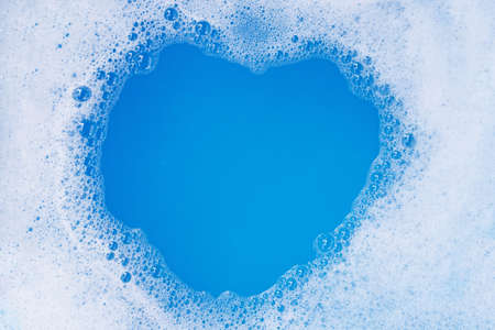 Frame made of detergent foam bubble. Blue background. Top view