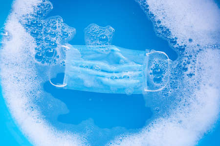 Protective medical mask  soak in powder detergent water dissolution before washing. Hygiene coronavirus (Covid-19) protection concept. Top viewの写真素材