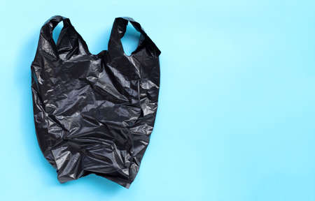 Black plastic bag on blue background. Copy spaceの写真素材