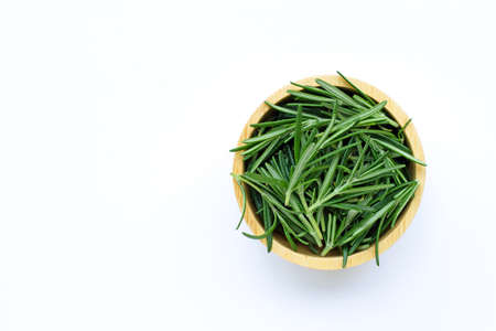 Fresh rosemary leaves on wooden bowl on  white background. Top viewの写真素材