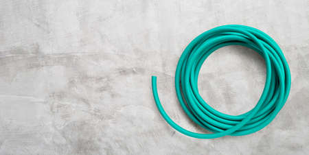 Green garden hose on concrete background. Copy spaceの写真素材