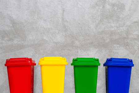 Red, Yellow, Green and Blue Recycle Bins. Concrete wall background. Copy spaceの写真素材