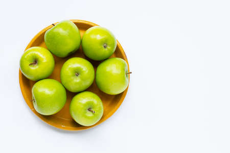 Fresh green apples on yellow plate on white background. Top viewの写真素材