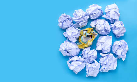 White and yellow crumpled paper balls on a blue background. Top view with copy spaceの写真素材