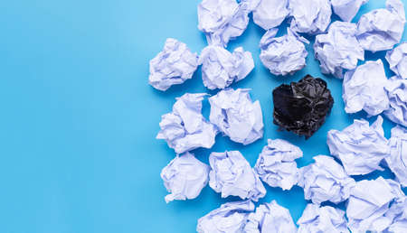 White and black crumpled paper balls on a blue background. Top viewの写真素材