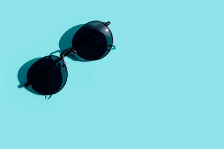 Sunglasses on blue background. Top view with copy space